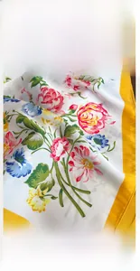 Close-up of vibrant floral patterns and yellow precision stitching on ivory silk scarf