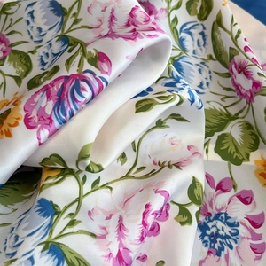 Detail of silk-like satin scarf with vibrant floral print and elegant glossy texture
