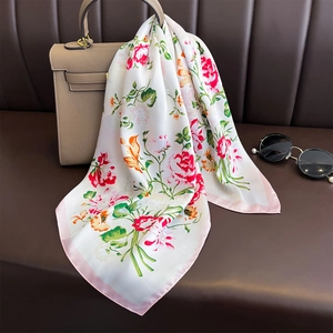 Elegant floral silk square scarf with pink blossoms draped over a designer handbag