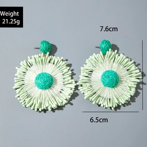Detail of handmade raffia earrings in green and white tones with size and weight markers
