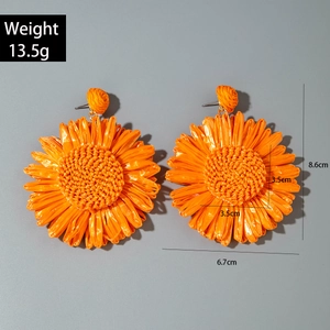 Detailed view of woven raffia sunflower earrings showing 8.6cm height and weight