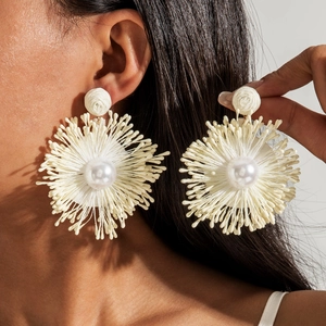 Detailed view of handmade raffia flower earrings featuring a large center faux pearl