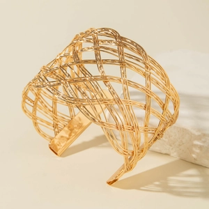 Detailed view of wide gold mesh bracelet featuring intricate woven hollow metal design