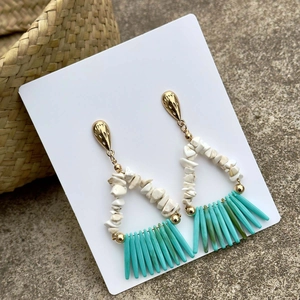 Detalle de pendientes boho con piedras blancas y borlas tubulares verde azulado