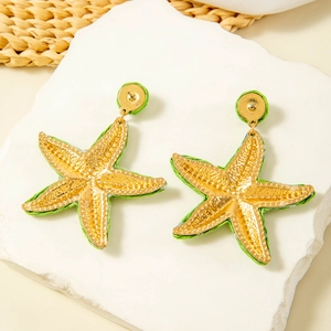 Handmade raffia star earrings with gold metal accents in green beach resort style