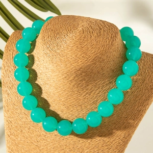 Detail of translucent mint green acrylic beaded necklace on a woven texture bust stand