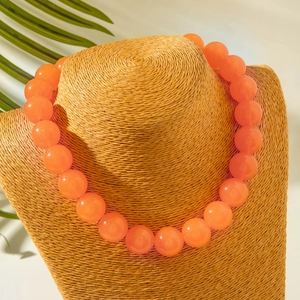 Macro detail of vibrant orange acrylic beaded necklace on woven neck display stand
