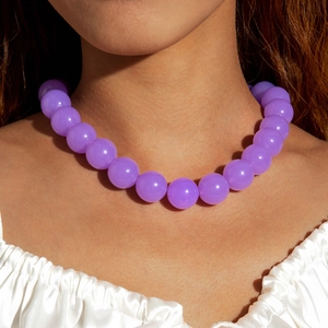 Close-up of vibrant purple acrylic bead necklace worn with a white satin ruffle blouse