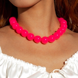 Close-up of chunky fluorescent pink acrylic bead necklace worn on a model with white satin