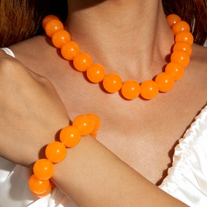 Close-up of vibrant orange acrylic beaded necklace and matching bracelet set