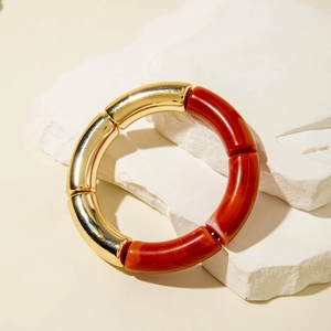 Close-up of marble patterned amber resin and golden metal tube elastic bamboo bracelet