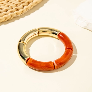 Detail of amber acrylic and gold curved tube segments on a vintage style bracelet