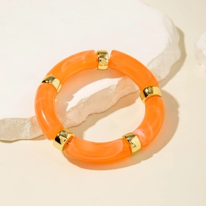 Macro detail of vibrant orange marble resin acrylic tube bracelet with gold spacers