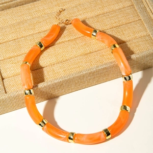 Close-up of orange marble acrylic tube beads with gold metal spacers on jewelry display