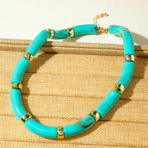 Detailed close-up of blue marble acrylic tube bracelet with golden spacers on a linen stand