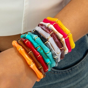 Detail of colorful acrylic bamboo tube bracelets with gold beads on a model's wrist