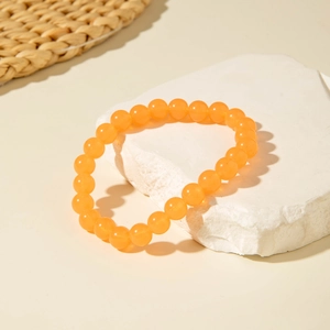 Close-up of translucent orange round beads on a stone display with warm lighting