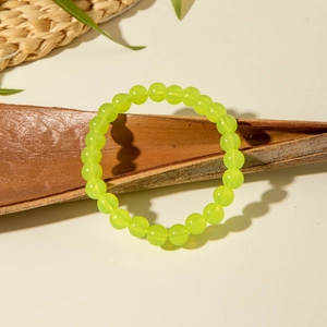 Detail of neon green acrylic beaded bracelet on natural tree bark with sharp shadows