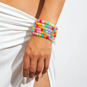 Close-up of vibrant rainbow acrylic beaded bracelets in dopamine style on a female wrist