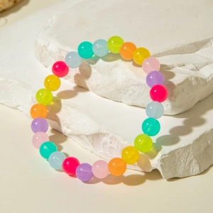 Close-up of colorful translucent acrylic beads on white stone with natural sunlight shadows