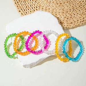 Close-up of colorful faceted acrylic beads on a set of six elastic bracelets displayed on stone