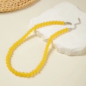 Detail of yellow round beaded necklace with a silver lobster clasp on a stone display