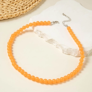 Detail of orange round acrylic beads necklace with silver lobster clasp on stone tray
