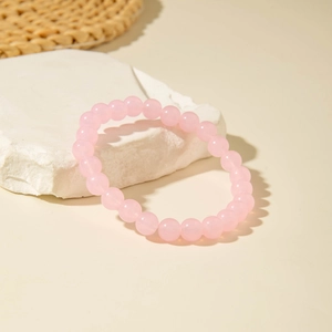 Minimalist beaded bracelet with translucent pink acrylic beads on a stone pedestal