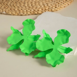 Detail of neon green oversized matte floral earrings on a decorative stone base