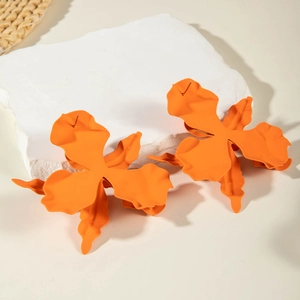 Close-up of vibrant orange orchid flower earrings on a natural stone base