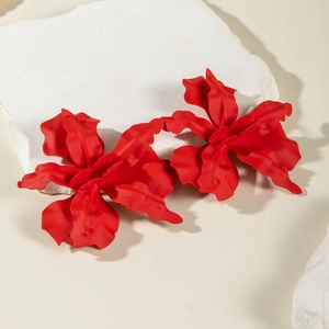 Macro view of matte red floral earrings with wavy 3D petals on a white stone background