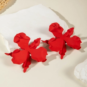 Macro detail of red matte flower stud earrings showing textured 3D petals and finish