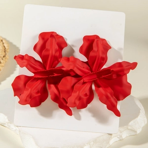 Detail of red matte enamel flower earrings with wavy petals on a textured stone base