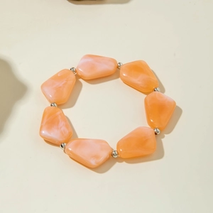 Détail de perles en acrylique orange bohème avec texture marbrée sur le bracelet