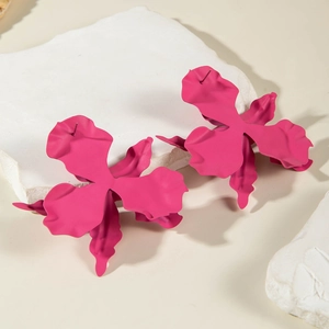 Exaggerated matte magenta orchid petal earrings displayed on white marble stone