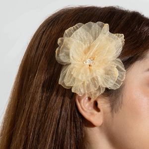 Détail d'une pince à cheveux fleur 3D en tissu champagne avec perles sur cheveux bruns