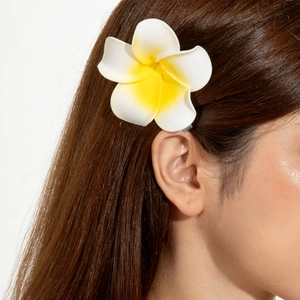 Gros plan d'une pince à cheveux fleur de frangipanier blanche et jaune avec pince métal
