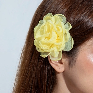 Détail d'une pince à cheveux fleur en polyester jaune 3D portée par un mannequin