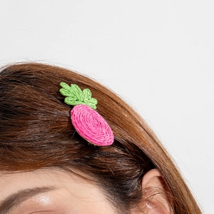 Gros plan d'une pince à cheveux en forme de carotte tressée rose sur cheveux bruns