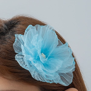 Détail d'une pince à cheveux fleur 3D bleu ciel avec pétales en tissu translucide léger
