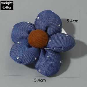 Détail d'une pince à cheveux fleur en denim bleu avec strass argentés et coeur marron