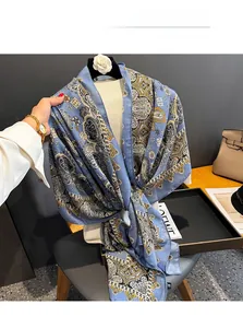 Detailed view of a blue paisley print scarf with soft texture draped over a white sweater