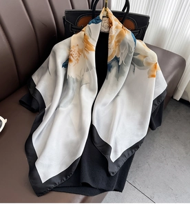 Silk satin square scarf featuring watercolor floral prints and black borders on a bag