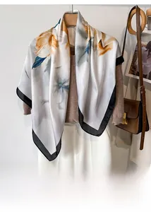 Floral silk-like scarf tied on a hanger, styled with a brown knit sweater and white pants