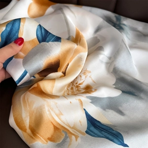 Elegant floral print satin scarf with golden flowers and blue leaves on white fabric