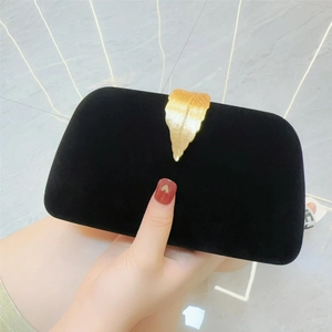 Detail of elegant black velvet evening clutch featuring a gold leaf metal clasp