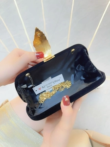 Detail of the black velvet evening clutch interior with golden leaf clasp and chain strap