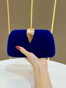Detail of royal blue velvet evening clutch featuring a gold leaf-shaped metal clasp