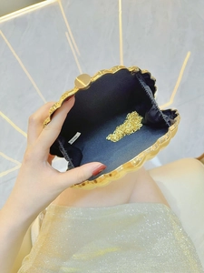 Golden shell-shaped metal evening clutch bag with chain strap and shiny ribbed finish