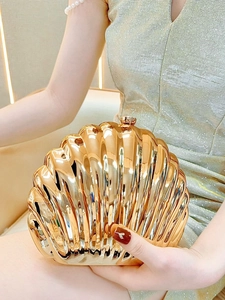 Close-up of a golden seashell evening clutch bag with high-gloss metallic texture and ball clasp